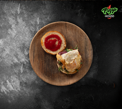 Burger mit aufgeschlagenem Brötchen: Spiegelei auf Rindfleischpatty, frischer Rucola und rote Zwiebeln – dazu goldene Pommes auf einem Holzbrett von oben fotografiert.