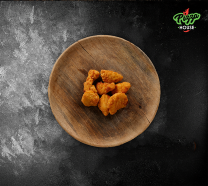 6 Chicken Nuggets auf rustikalem Holzbrett – goldbraun frittiert und gleichmässig angerichtet, Draufsicht.