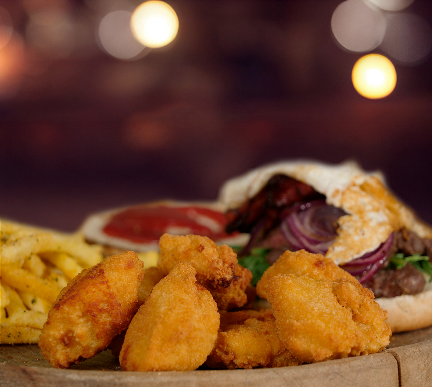 Knusprige Chicken Nuggets im Fokus – goldbraun frittiert, vorne serviert, dahinter der Burger mit Ei und frischem Rucola.