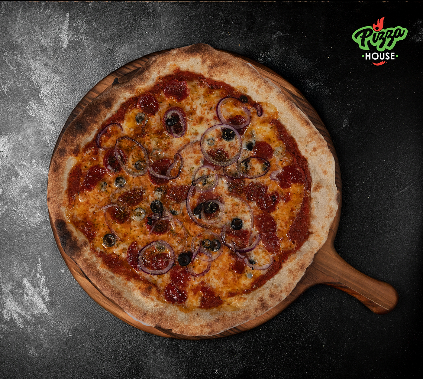 Pizza Calabrese von oben – belegt mit scharfer Salami, roten Zwiebelringen, schwarzen Oliven und Oregano, serviert auf Holzbrett mit dunklem Hintergrund.