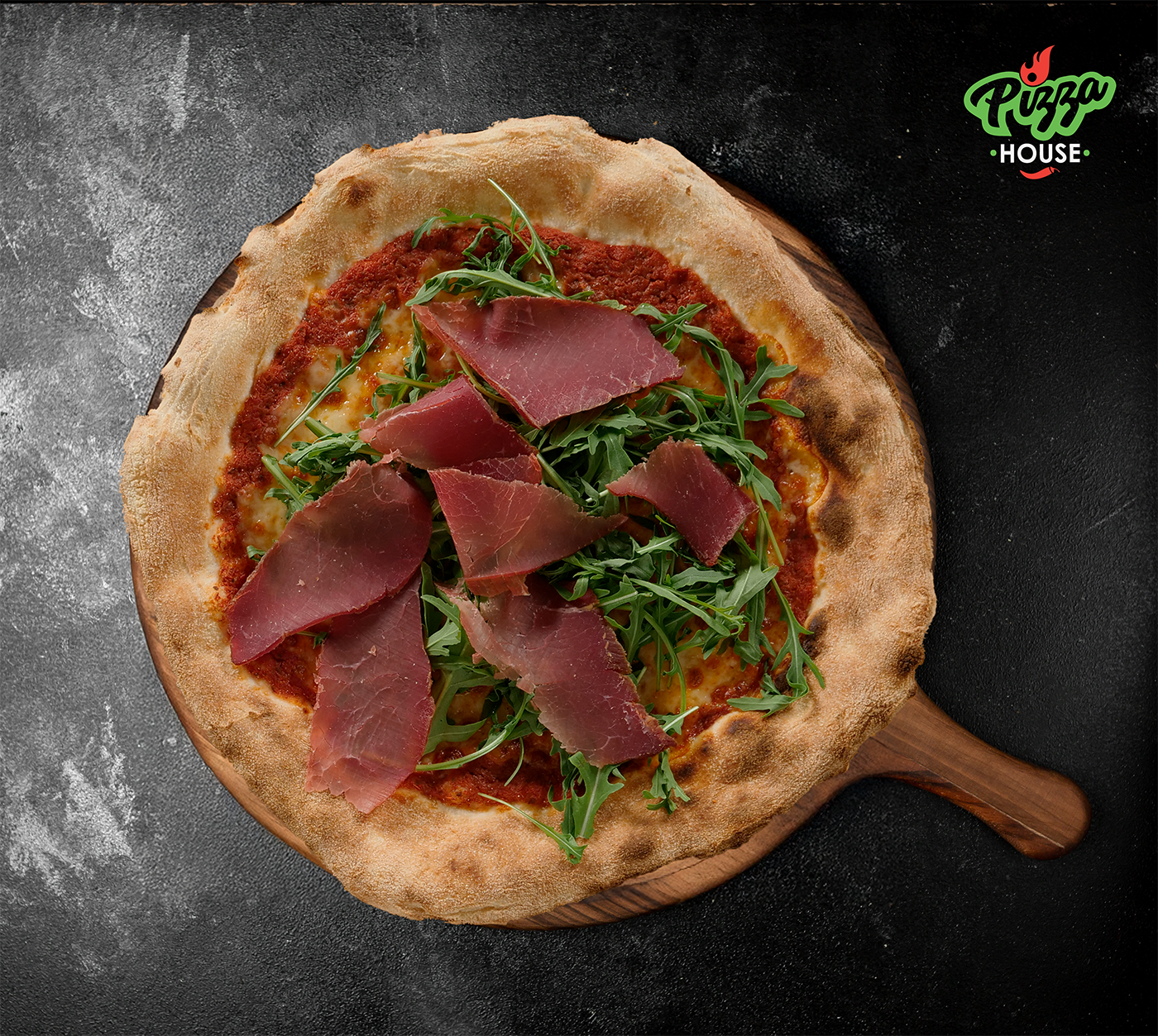 Pizza del Valais von oben – mit Rindstrockenfleisch, Rucola und Parmesan auf goldbraunem Rand serviert.