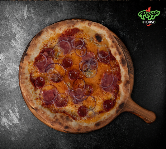 Pizza La Mana von oben – belegt mit roten Zwiebelringen, Schinken, scharfer Salami und geschmolzenem Gorgonzola, serviert auf Holzbrett mit dunklem Hintergrund.