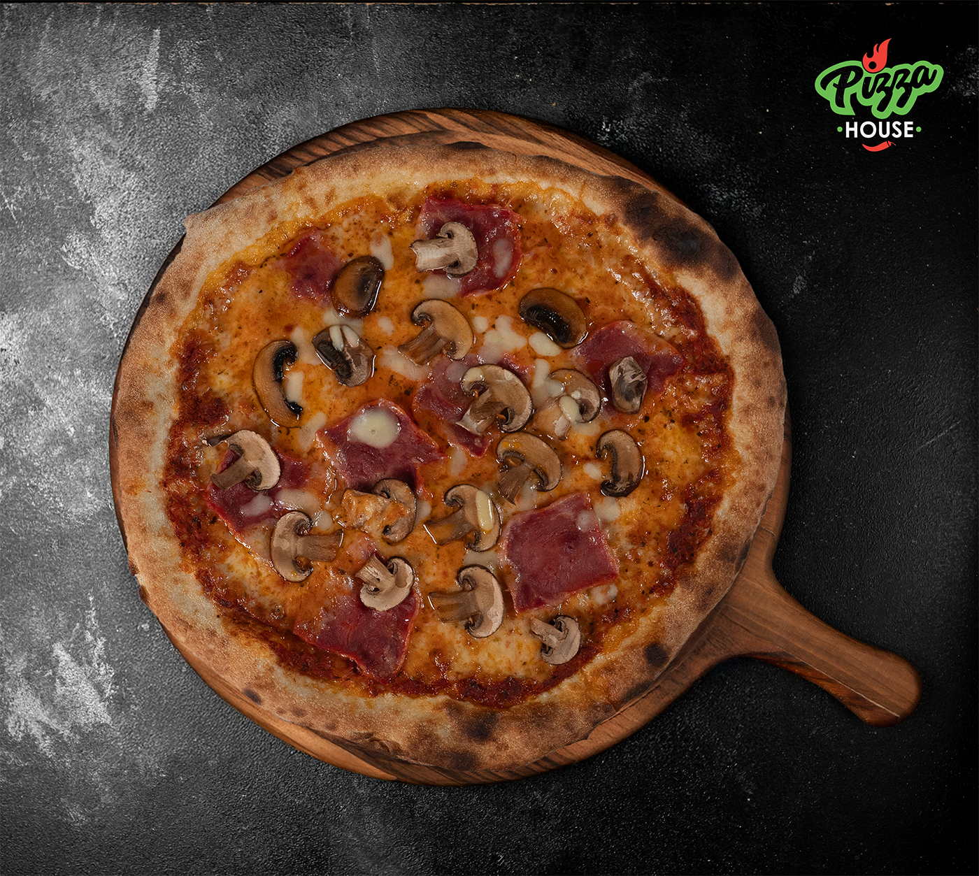 Pizza Prosciutto e Funghi von oben – goldbrauner Rand, großzügig belegt mit Champignons und Schinken, serviert auf Holzbrett mit dunklem Untergrund.