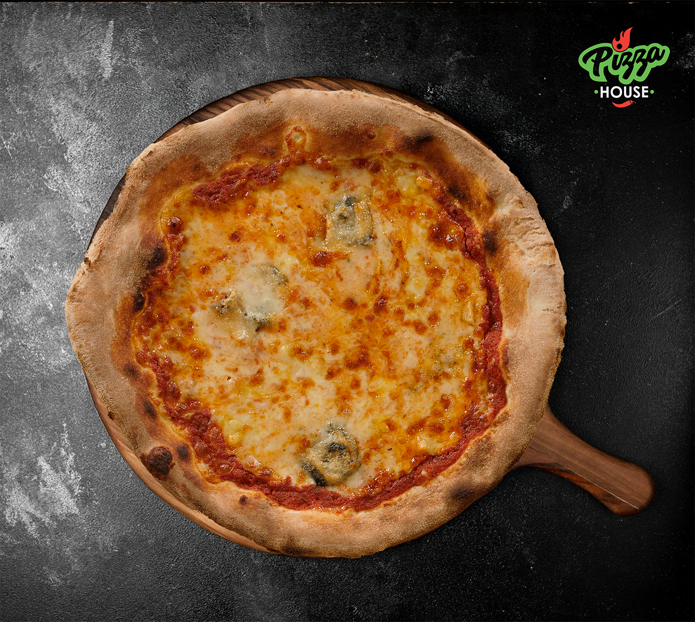 Pizza Quattro Formaggi von oben – goldbraun gebackene Käsekruste auf Tomatensauce, serviert auf Holzbrett vor dunklem Stein-Hintergrund.