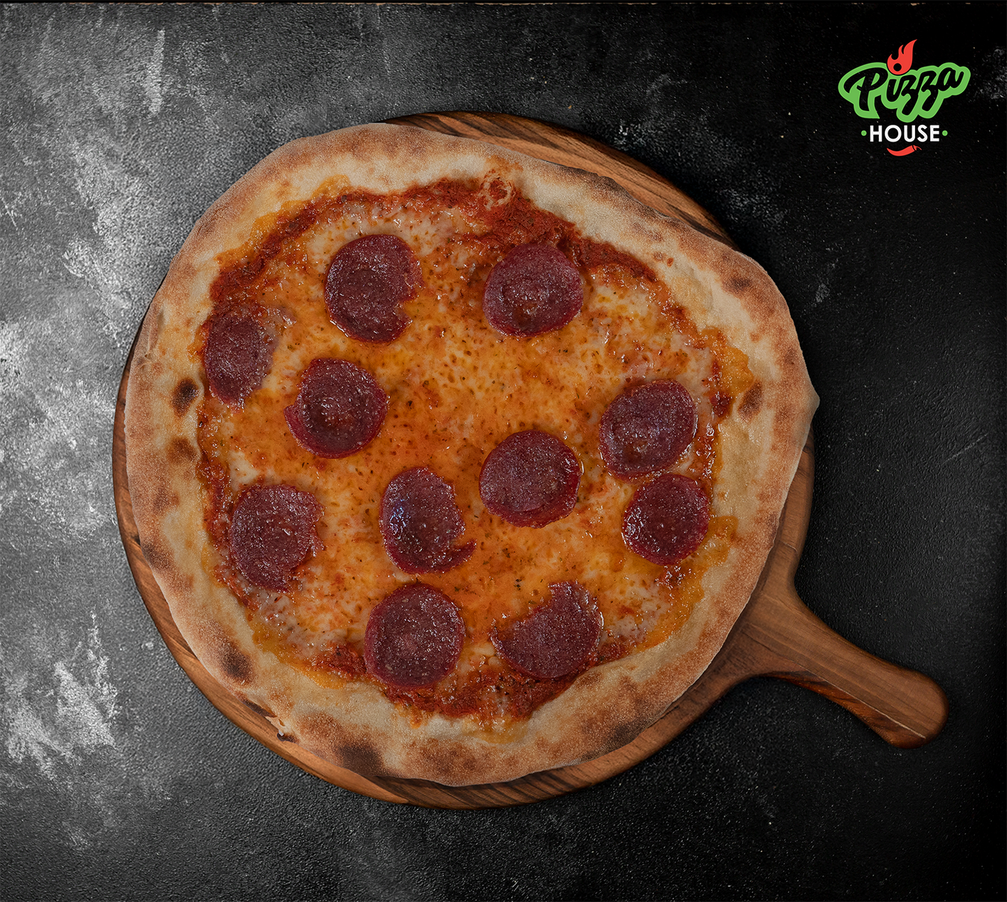 Pizza Salami von oben – perfekt gebackener Rand, goldgelber Käse, runde Salamischeiben, serviert auf Holzbrett mit dunklem Hintergrund.